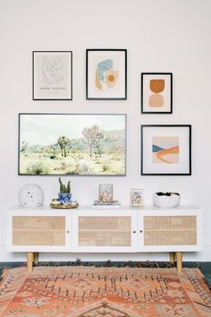 a living room with pictures hanging on the wall and a rug in front of it