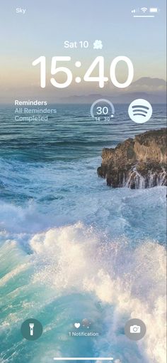 an iphone screen with the time displayed on it and waves coming in from the ocean