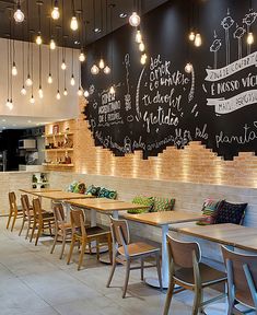 the interior of a restaurant with tables and chairs in front of a chalkboard wall