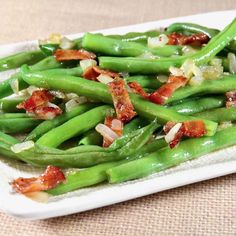 green beans with bacon and onions on a white platter, ready to be eaten