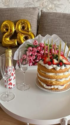 a cake with strawberries and berries on it sitting on a table next to champagne glasses