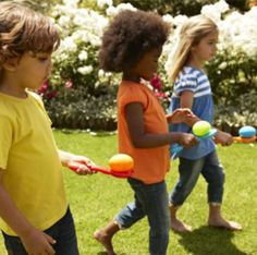 three children playing with plastic balls in the grass