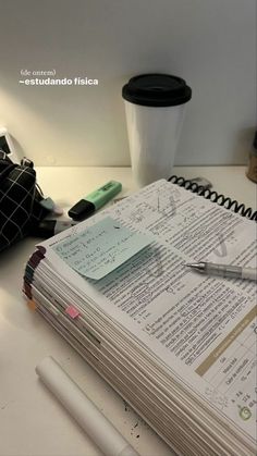 a stack of papers sitting on top of a table next to a cup and pen