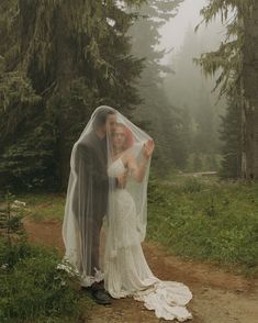 a bride and groom pose for a photo in the woods on a foggy day