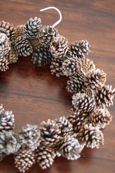 a wreath made out of pine cones sitting on top of a wooden table