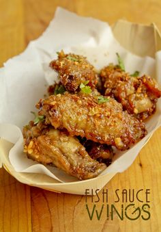 some fried food is in a basket on a wooden table with white napkins and green garnishes