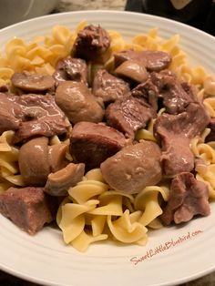 a white plate topped with pasta and meat