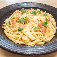 a black bowl filled with pasta and garnished with parsley