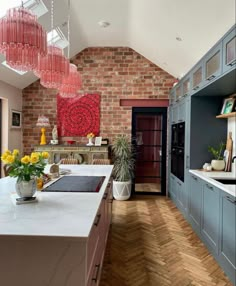 a kitchen with an island and brick wall in the back ground, surrounded by wooden flooring