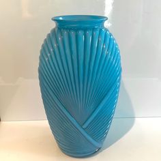 a blue vase sitting on top of a table next to a black container with a white wall in the background