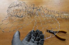 a pair of scissors and wire sitting on top of a wooden table next to some wire