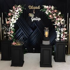 a black and gold wedding arch with flowers, candles and other decorations on the side