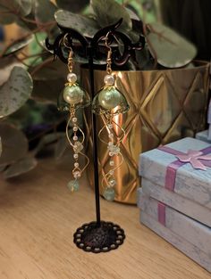 These handmade olive green jellyfish earrings with pearls and crystals are perfect gifts for anyone who loves the ocean. Delicate light green glass sits among white pearls with small jade crystals dangling from hand-twisted wire swirls. You can select either small or large jellyfish sizes paired with gold or silver embellishments. Average total length of each earring is 4 inches. Green Pearl Drop Earrings For Gift, Green Pearl Drop Earrings As Gift, Green Dangle Jewelry With Bead Caps, Bead Cap Drop Earrings For Gift, Bead Cap Drop Earrings As Gift, Bead Caps Drop Earrings As Gift, Handmade Green Pearl Earrings For Gift, Green Pearl Earrings For Gift, Green Pearl Earrings As Gift