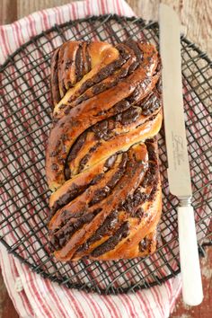 chocolate swirl bread sitting on top of a wire rack with a knife next to it