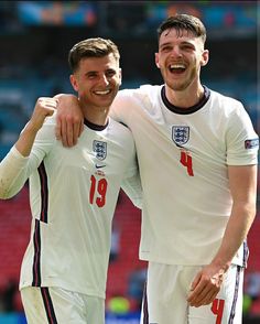 two soccer players standing next to each other with their arms around one another and smiling at the camera