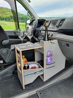 an open trunk in the back of a vehicle filled with bottles and glasses, next to a wine glass