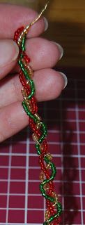 a hand holding a red and green beaded bracelet