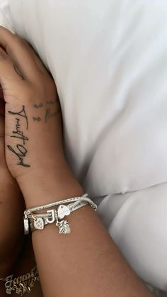 a woman laying in bed with her arm wrapped around the pillow and tattoos on her arm