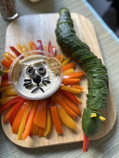 a plate topped with carrots and vegetables next to a cucumber on a cutting board