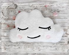 a white cloud pillow with eyes closed on a wooden surface, surrounded by pink and white confetti