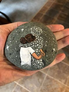 a hand holding a rock with a painting on it