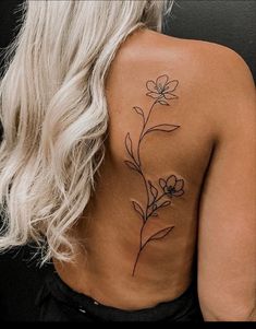 the back of a woman's shoulder with a flower tattoo on her left side