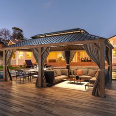 an outdoor living area with couches, tables and a gazebo at night time