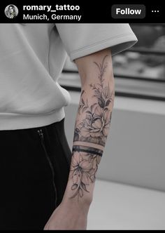 a woman's arm with flowers and a ribbon tattoo on it, in black and white