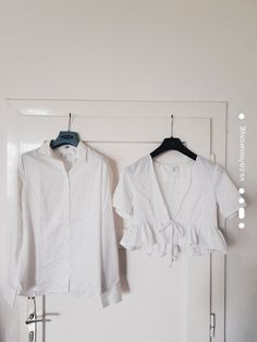 two white shirts hanging on the wall next to each other with clothes pins attached to them