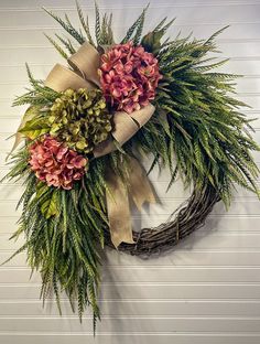 a wreath with flowers and greenery hanging on a wall