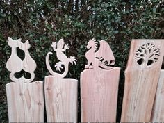 three wooden cutouts of different animals on top of each other in front of some bushes