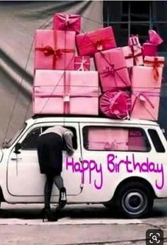 a white car with pink presents on the top and purple lettering that says happy birthday