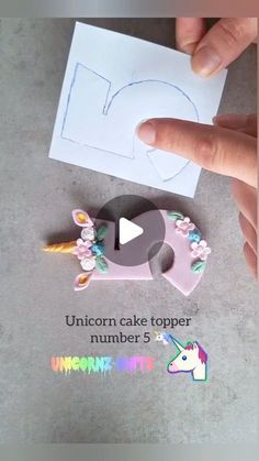 someone is cutting out a unicorn cake topper with scissors and paper on the table