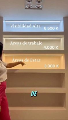 a woman pointing at the wall in front of an advertismal sign that reads,