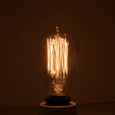 an old fashioned light bulb sitting on top of a wooden base in a dark room