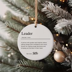 a white ornament hanging from a christmas tree with the words leader on it