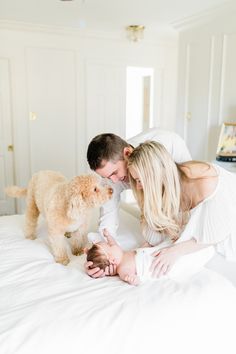 a man and woman are laying on a bed with a dog in front of them