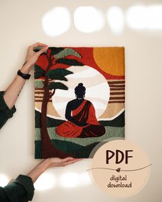 a person is holding up a painting with a buddha figure on it and palm trees in the background