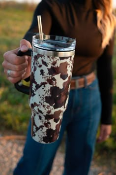 a woman is holding a coffee cup with straws in her hand and wearing jeans