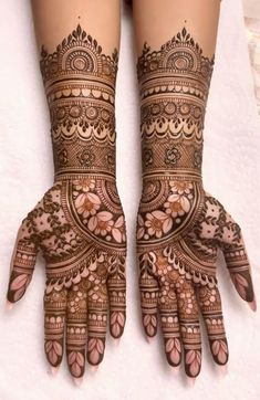 two hands with henna tattoos on them, one is showing off the intricate design