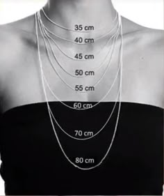 a woman wearing a black top with three different lengths of necklaces on her neck