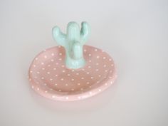 a pink and white polka dot covered dish with a cactus in it's center