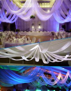 two pictures of the inside of a banquet hall with white draping and blue lights