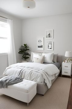 a bedroom with white bedding and pictures on the wall, along with a footstool