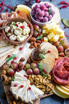 an assortment of cheeses, fruits and nuts on a cutting board