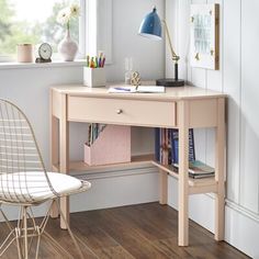 a desk with a chair, lamp and bookshelf in front of a window