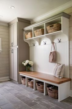 a white bench with baskets on it in the middle of a walk - in closet