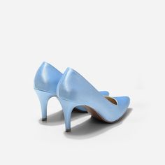 a pair of blue high heeled shoes on a white surface with one shoe in the middle