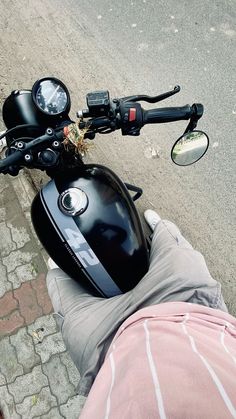 a person's feet on the handlebars of a motorbike with a black helmet