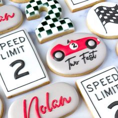 decorated cookies with race cars and numbers are displayed on a white tablecloth for display